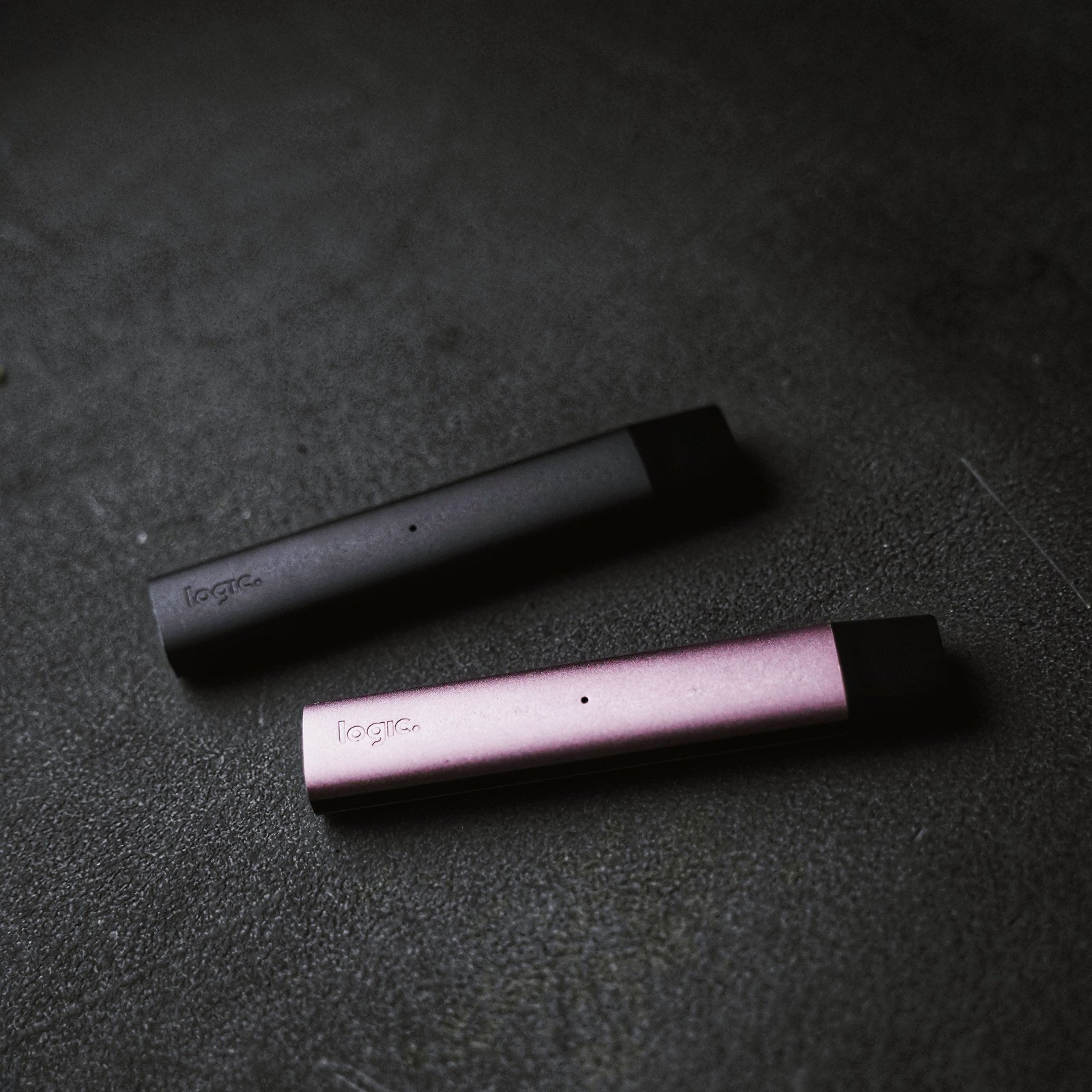 Two slim pod devices on a dark textured surface