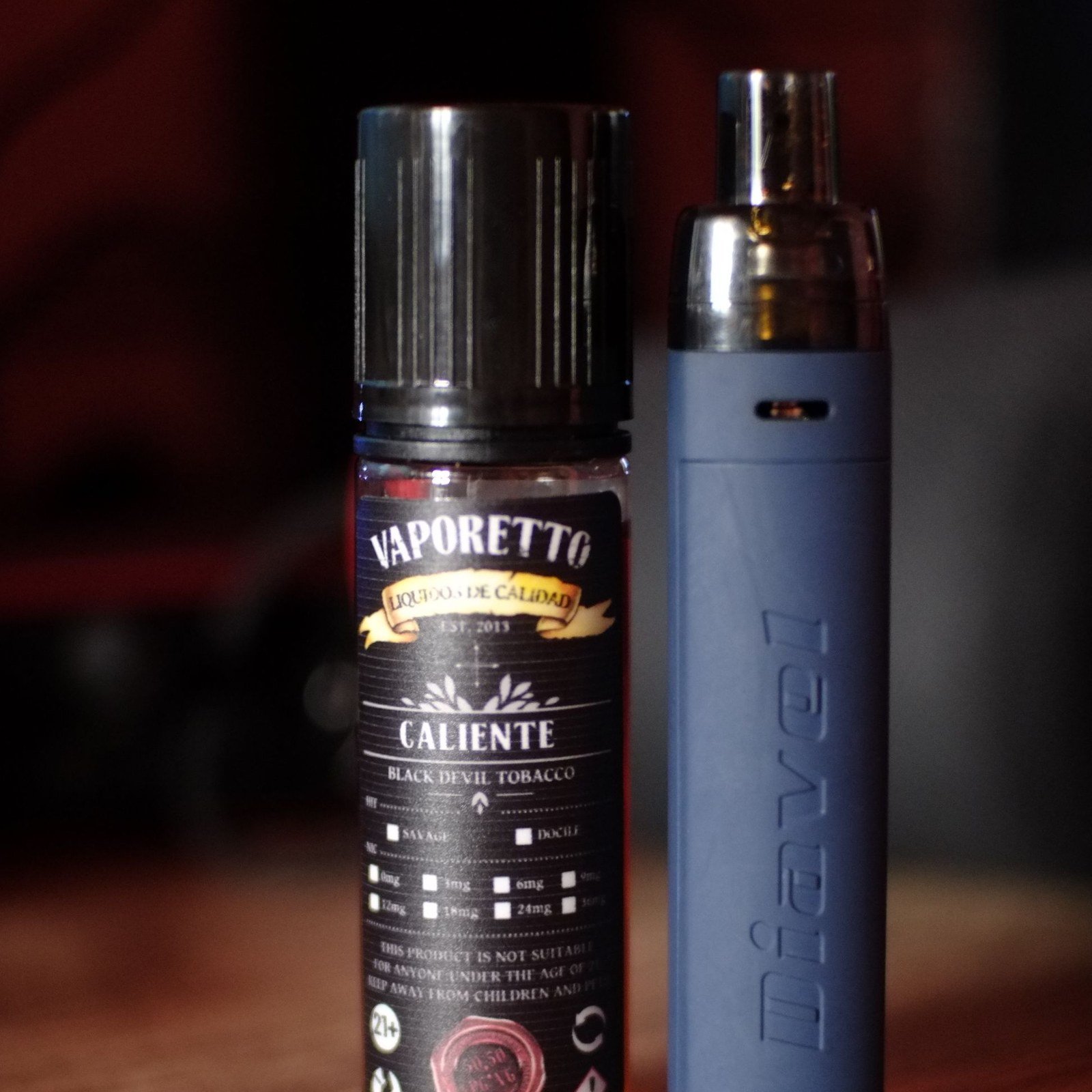 E-liquid bottle beside a vapour device on a dark ground